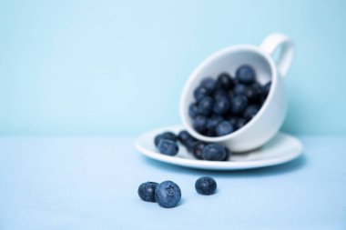 Blueberries on the background of a blurred mug with berries