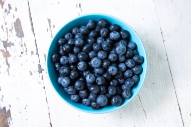 Top view of round bowl with blueberries on wooden table