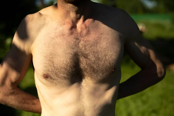 Hairy chest of man on beach. Guy\'s chest is in sunlight. Body details. Middle-aged man.