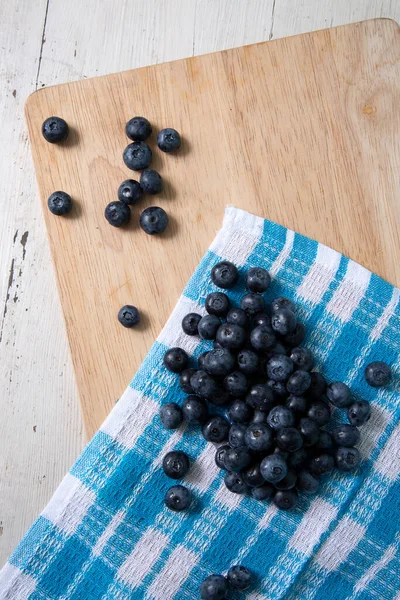 Top view of blueberries on wooden cutting board. Vertical photo