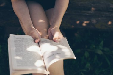 Young lady reading book,  girl's hands and open pages close up. Country vacances on open air, copy space