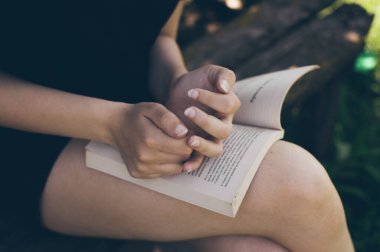 Young lady reading book,  girl's hands and open pages close up. Country vacances on open air