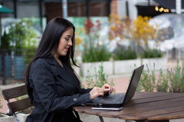elegant woman working outdoor, using a laptop computer in a cafe.