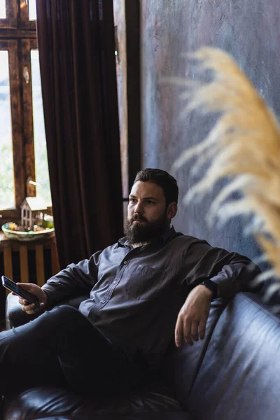 Man Beard Smartphone Sitting Leather Sofa — Fotografia de Stock