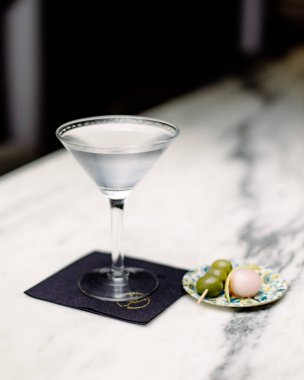 Ice cold martini sits on white marble bar