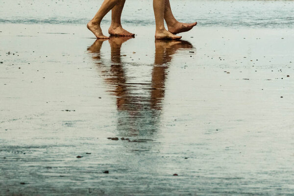 legs of people walking on the beach