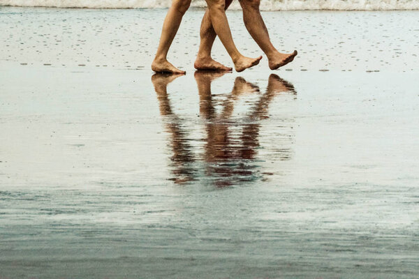 legs of people walking on the beach