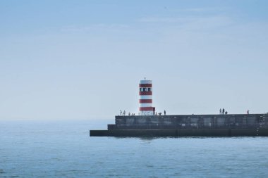 lighthouse on the pier with fishermen