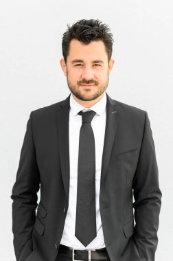 Çekici beyaz adam siyah takım elbiseli kameraya bakıyor.