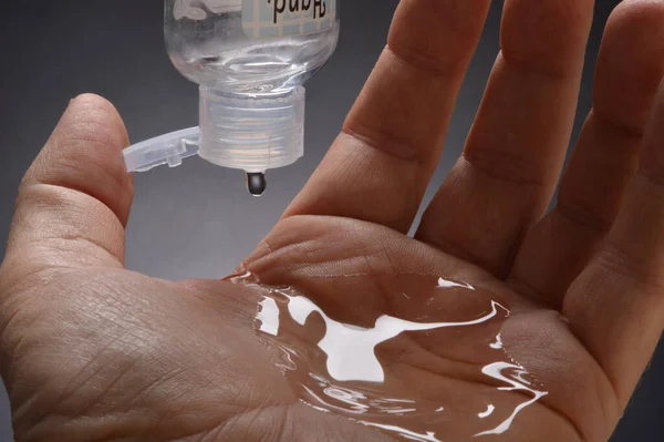 Hand sanitizer dripping into and overflowing from hand