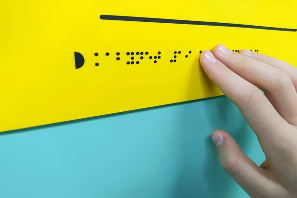 Child's hand is reading braille text