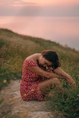 portrait girl in summer on mountain with her head bowed on her knees