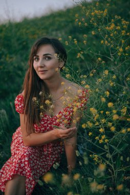portrait of a girl in the summer on the grass cut yellow wildflowers