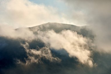 White clouds floating over volcanic mountainous terrain
