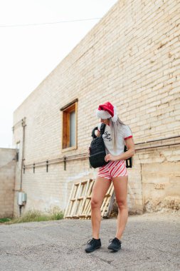 Young woman wearing santa hat putting on a weighted vest for a c