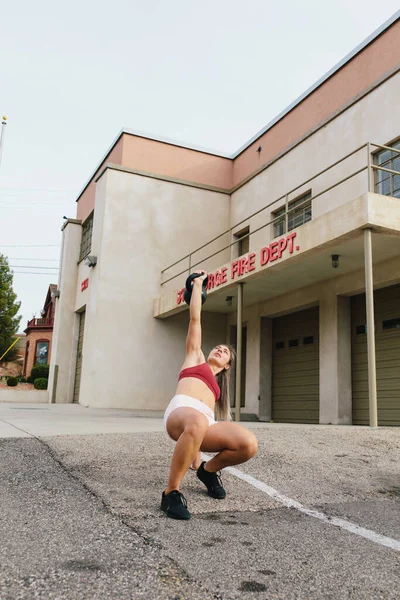 Young Blonde Woman Doing Kettlebell Turkish Gettup Front — стоковое фото