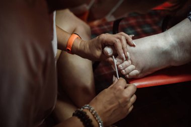 Pedicurist grinds nails of client with nail file