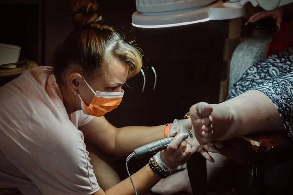 Masked Pedicurist Grinds Dry Skin Client Foot — Stockfoto