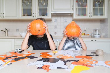 Çocuklar balkabağı tutuyor ve Cadılar Bayramı tatiline hazırlanıyorlar..