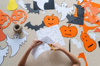 Elinde makas olan bir kızın elleri Cadılar Bayramı için el işi yapar..