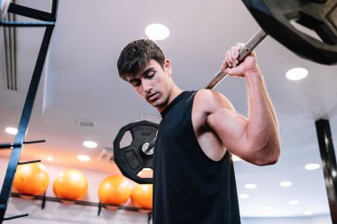 Muscular male athlete exercising with barbell