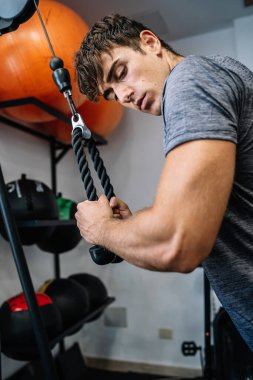 Muscular male athlete pulling cable