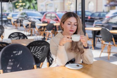The girl is looking at a mug of coffee