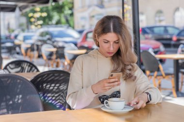 The girl makes photo on Phone in caffe on terrace.