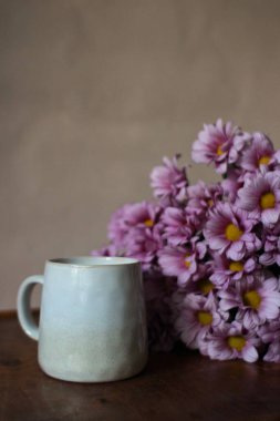 Gri kupa ve pembe çiçekler