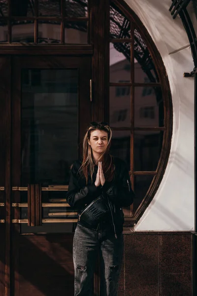 黒いジャケットを着た少女が建物の壁の前に立ち — ストック写真