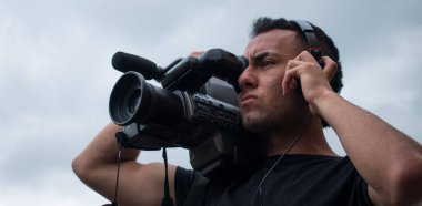 Bulutlu bir günde büyük bir kamerayla çekim yapan bir adam.