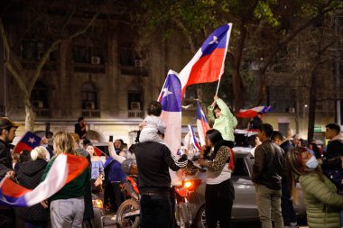 Çocuklar Şili bayraklarını kaldırırken ebeveynlerinin omuzlarında oturuyorlar.