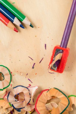 Tahta bir masada renkli bir kalemi keskinleştirmek.