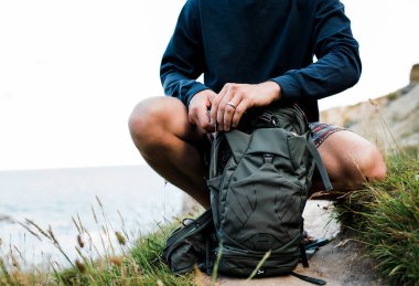 Adam yürüyüş yaparken sırt çantasını düzenliyor ve ayarlıyor.