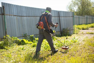 Worker mows lawn. Gardener with gasoline-powered lawn mower.