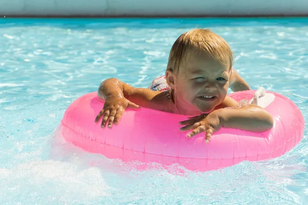 Küçük Bir Çocuk Havuzda Pembe Bir Yüzme Çemberinde Yüzüyor — Stok fotoğraf