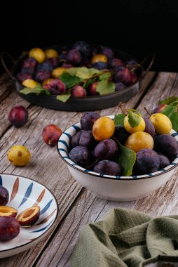 Tahta zemin üzerinde açık seramik tabakta taze erikler.