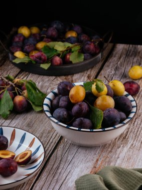 Tahta zemin üzerinde açık seramik tabakta taze erikler.