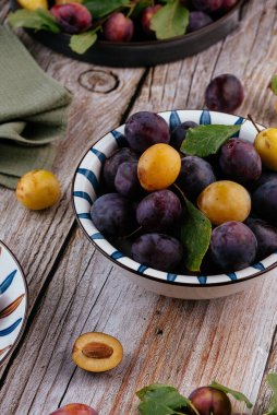 Tahta zemin üzerinde açık seramik tabakta taze erikler.