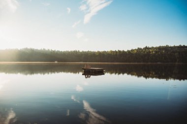 Güneşli bir yaz sabahında sakin bir gölde yüzen yüzme platformu.