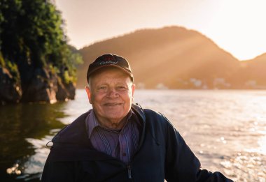 Portrait of smiling elderly man on a boat at sunset in Newfoundland.