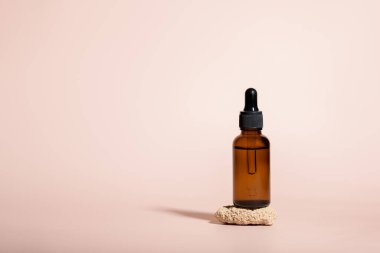 Kehribar cam damlatan şişeler bej arka planda taş üstüne serum