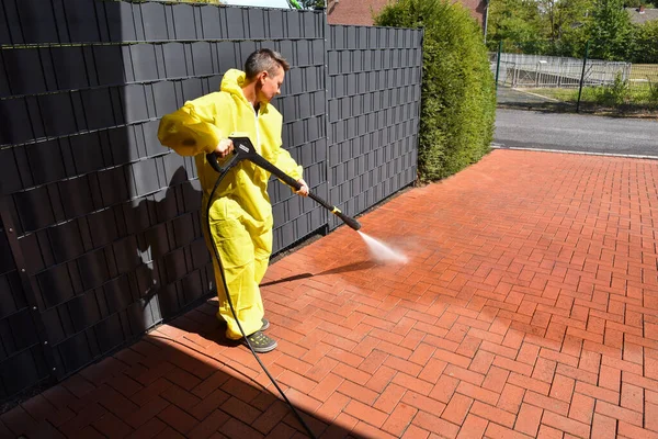 a woman cleans the terrace with a high-pressure cleaner