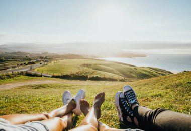 Sahilde gün batımına karşı üç kadının bacakları.