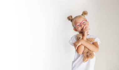 Gözlüklü ve elinde bir ayı olan mutlu bir kızın portresi.