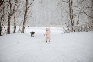 Genç bayan çocuk ve siyah evcil köpek Kış Harikası 'nda yürüyor