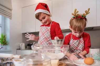 İki kardeş mutfakta Noel kurabiyesi pişiriyor.