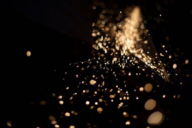 Karanlıkta kıvılcımlar. Metal öğütücü ışıklar. Öğütücü işinin ayrıntıları. Siyah arka planda küçük kıvılcımlar farklı yönlere uçar.