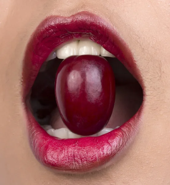 Close-up van het eten van de mond van de vrouw rode druif. — Stockfoto