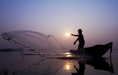 Fishermen are catching fish with a cast net. clipart